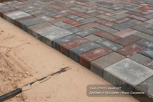 Участок с брусчаткой в Южно-Сахалинске: рабочий край, граница с газоном и подготовка к эксплуатации.