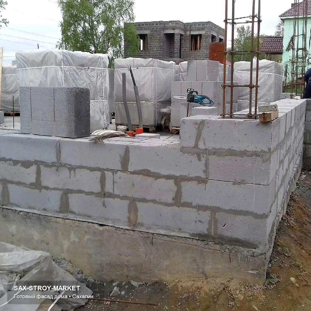 Готовый дом и участок: виден крыльцо, подъезд, двор, терраса и цокольная зона у места будущей отмостки. Такой ракурс нужен для подготовка к благоустройству при ветре и мокром снеге: какие переходы нужно учесть перед благоустройством.